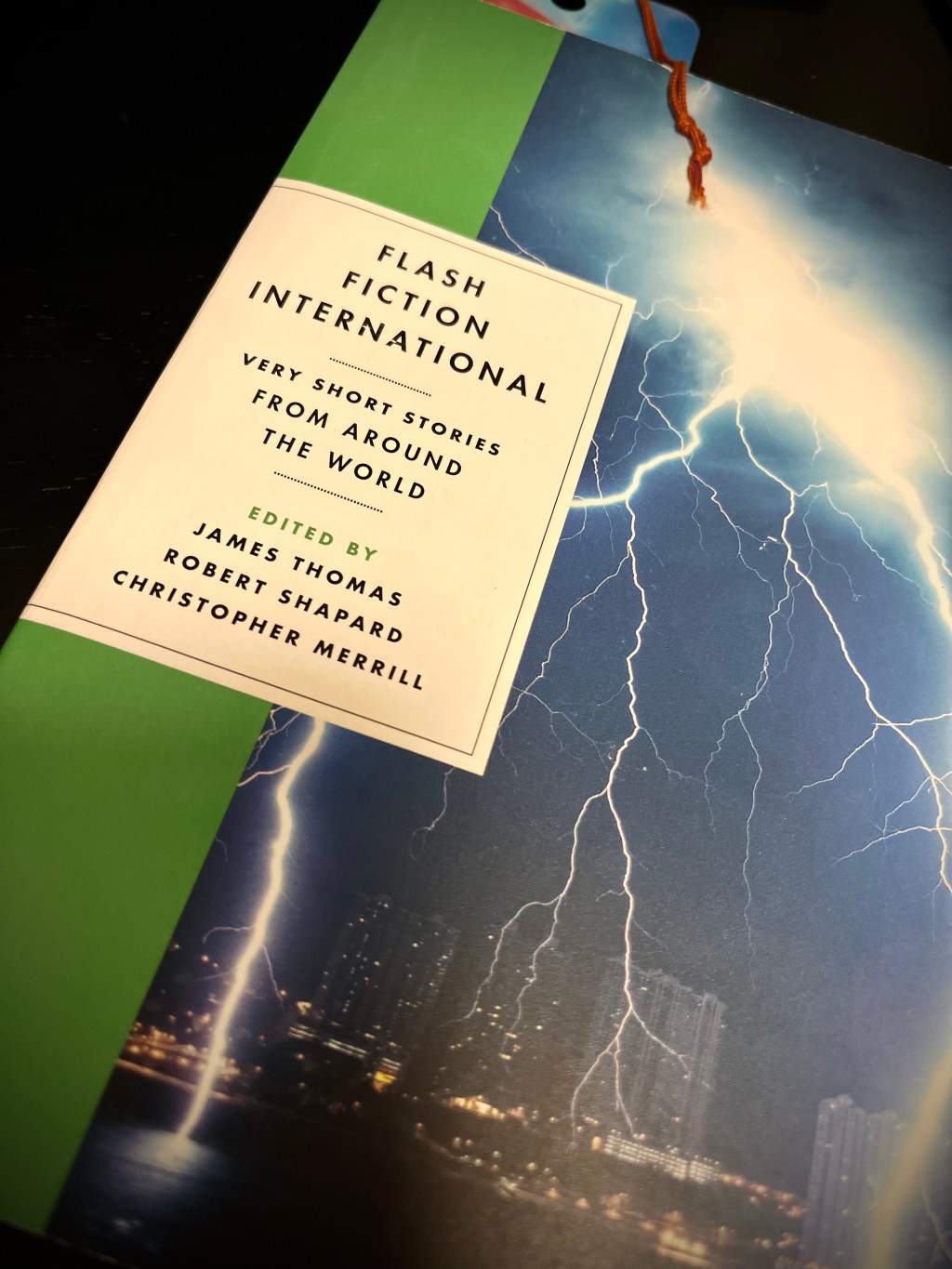 Angled picture of a copy of Flash Fiction International. Decorative.